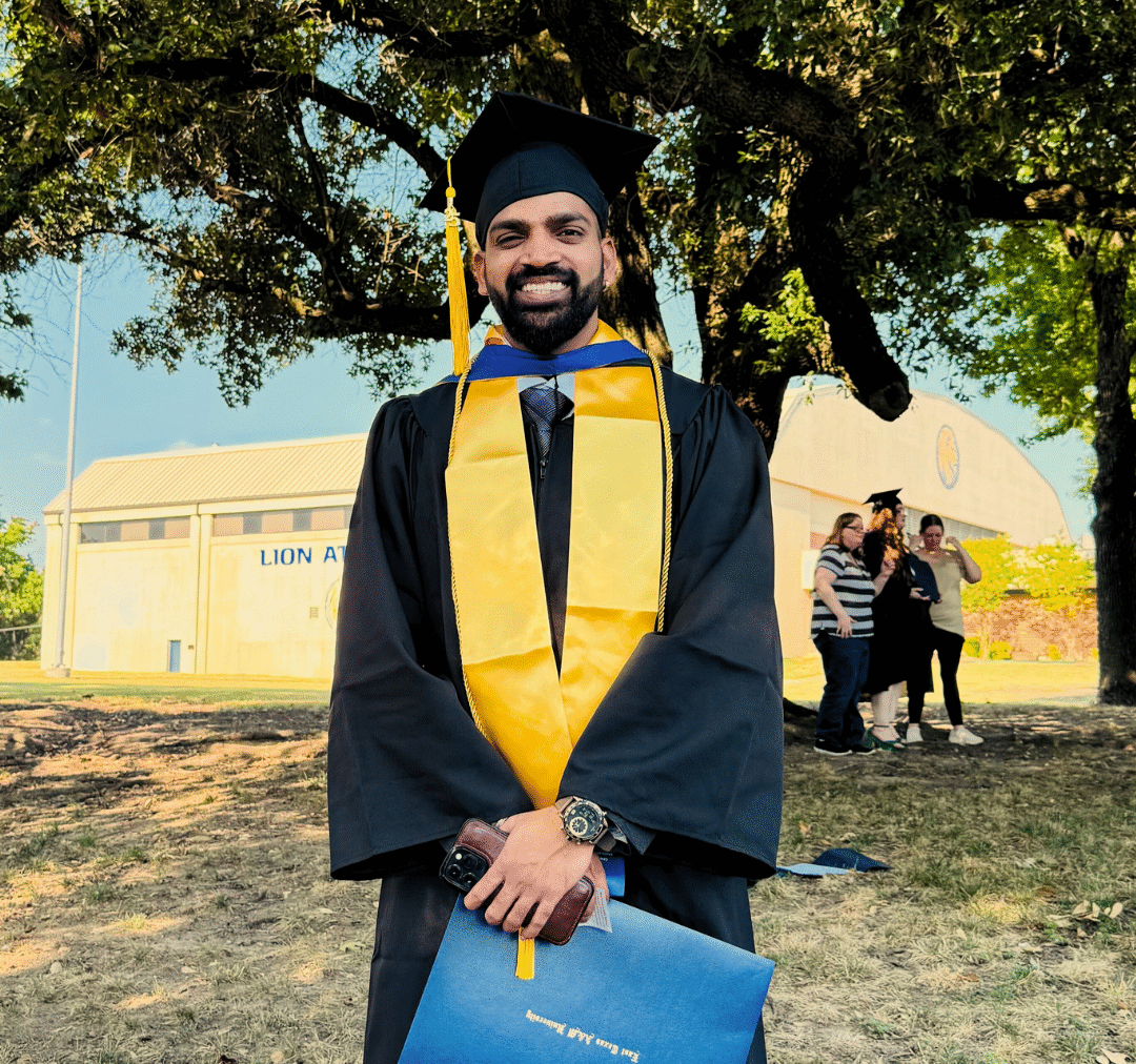 A college graduate in cap and gown posing for a photo.
