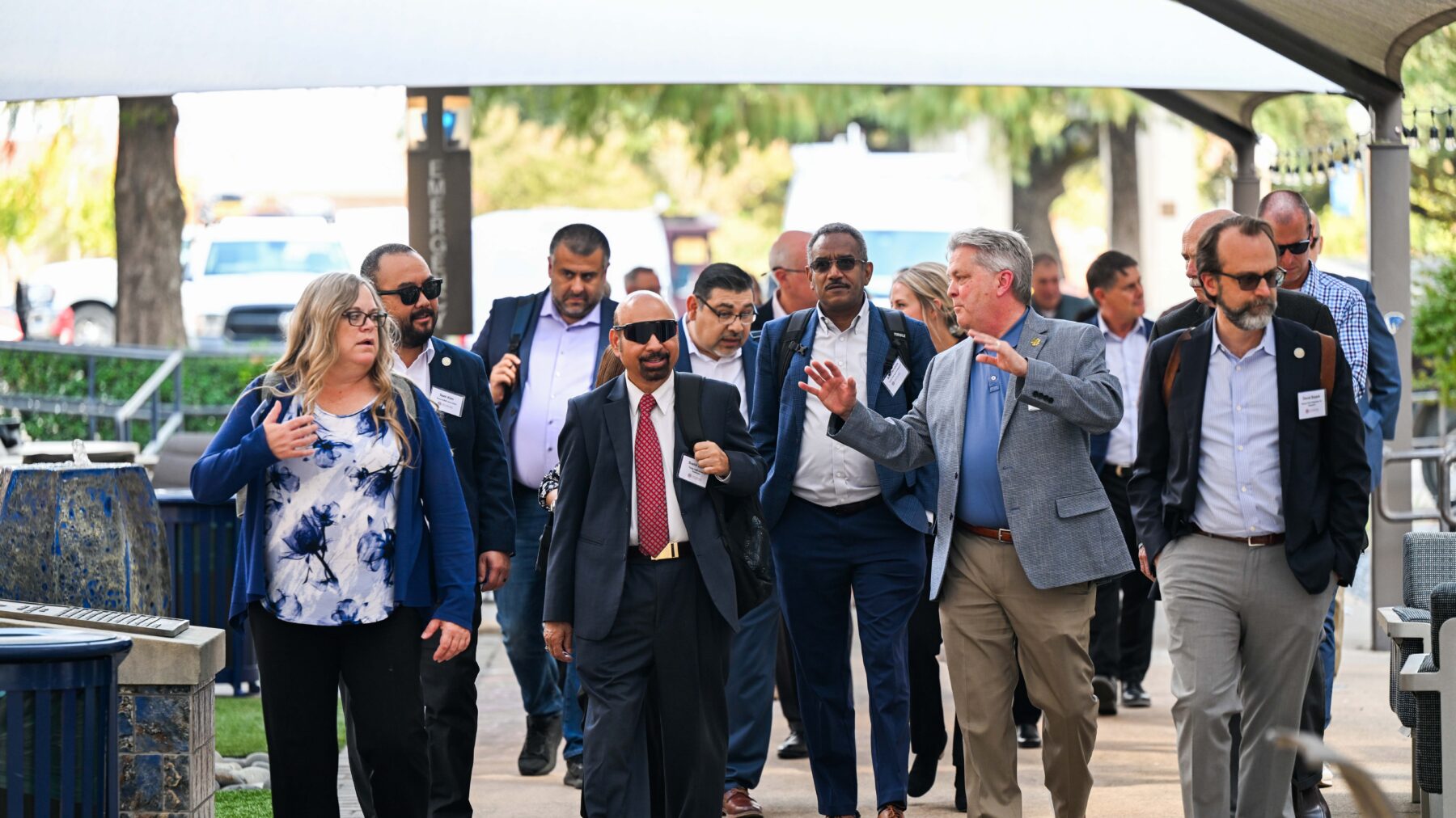 A tour guide points at something, and a group of people around him look toward where he is pointing. They are smiling.