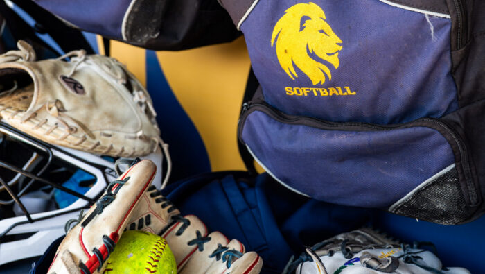 A photo of various softball equipment including gloves, a ball and a catcher's mask.